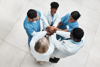 Fostering teamwork to improve patient outcomes. High angle shot of a group of medical practitioners joining their hands together in a huddle.