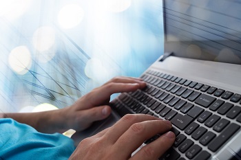 Mans hands typing on laptop notebook keyboard in the office.