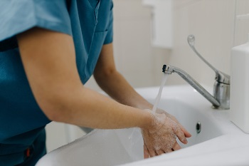 Female worker washing her hands meticulously with water.